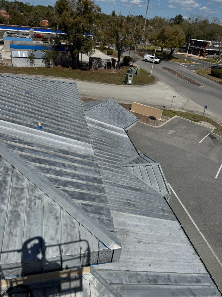 Aerial view of Williamsburg Vet Clinic roof after sandblasting — all blue paint removed, bare metal exposed across full 7000 sq ft